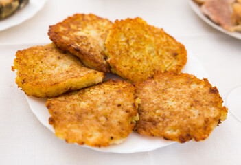 Potato pancakes with sour cream on white plate