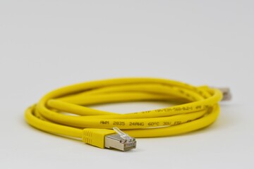 Den Helder, Netherlands. december 14, 2024. close up of a yellow ethernet cable on a white background.