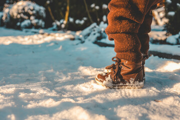 Close up of boots on feet, child walking in snow in winter