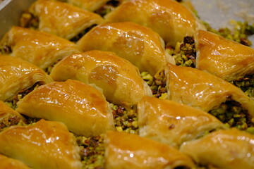 Close-up view of baklava with pistachios, walnuts and cream in a dessert shop selling traditional Turkish desserts. Şöbiyet, nightingale's nest, bird's eye baklava. Turkish culinary delights. Dessert 