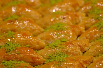 Close-up view of baklava with pistachios, walnuts and cream in a dessert shop selling traditional Turkish desserts. Şöbiyet, nightingale's nest, bird's eye baklava. Turkish culinary delights. Dessert 