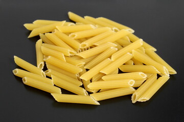 A small pile of pasta lies on a black background.	