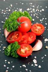  Sliced ​​tomatoes and pea-shaped peppers lie on a black stone background.	