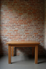 Simple wooden table sits against a rustic brick wall in a quiet room with subtle natural lighting._00003_