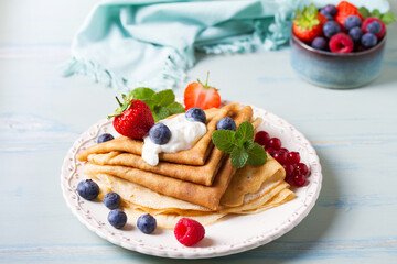 Crepes, thin pancake stack with yogurt and berries. Wrapped pancakes on a plate