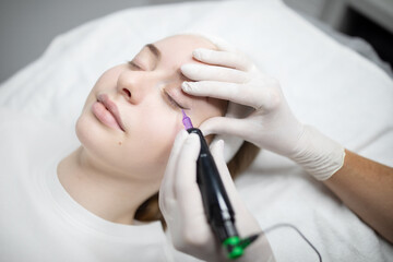 A beautician applies permanent makeup on a woman's eyebrows during a pampering session at a beauty salon. The process aims to enhance features with long-lasting results.