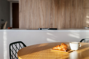 Enjoy a cozy moment with a croissant and coffee in a warm living space