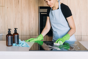 Housekeeper cleaning a modern induction stove in a contemporary kitchen