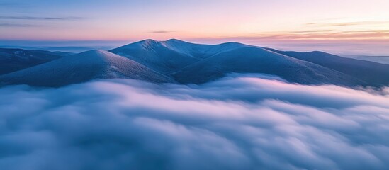 Aerial view of the picturesque Beskid Mountains shrouded in clouds at sunrise with vibrant colors illuminating the landscape