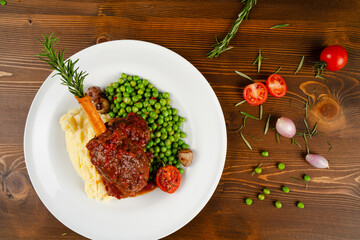 Lamb shank with sauce prepared in a modern style. Lamb shank served with mashed potatoes and peas in an elegant presentation. A delicious dinner.