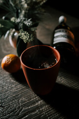 Craft Cup of Hot Mulled Wine Alongside a Bottle of Wine and Fresh Tangerine Creating a Cozy Winter Atmosphere