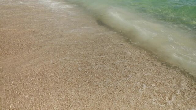 White crests of sea waves roll in and break into white foam on the sandy pebble shore of the beach on the island of Brač in Croatia. Tourism and beach recreation on the Adriatic coast.