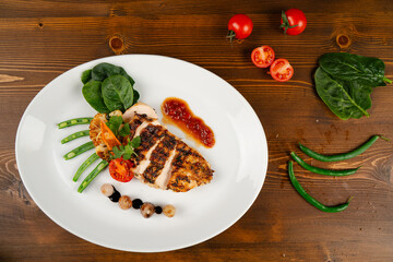 Delicious Grilled Chicken Fillet. Healthy lunch served with various vegetables and organic tomatoes.