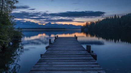 Serene lakeside view at dusk with a wooden dock reflecting on calm water surrounded by mountains and lush forests