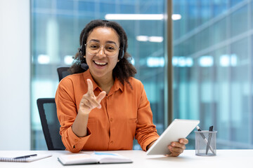 A cheerful professional wearing a headset holds a tablet during a customer support interaction. The setting is contemporary office, emphasizing efficiency and technology in delivering quality service