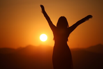 A joyful young Asian woman embraces the breathtaking beauty of a stunning sunset.