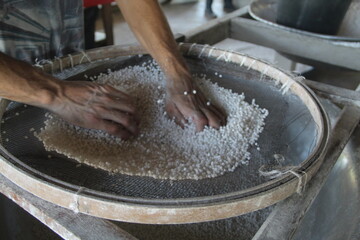 pessoa peneirando farinha de mandioca em cruzeiro do sul, no acre 