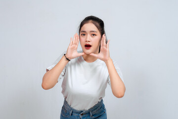 Surprised Asian woman reclines on her hands and shouting while looking at the camera over white...