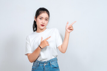 Excited Asian woman pointing at the copy space beside her, isolated on white background