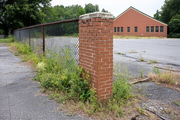 A broken fence in an abandoned lot, with wild plants growing around and through its gaps, symbolizing nature reclaiming space