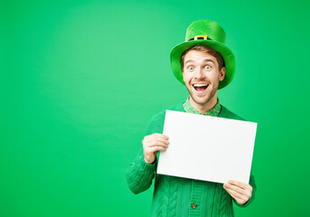 Excited young male in green St. Patrick's day attire holding blank sign