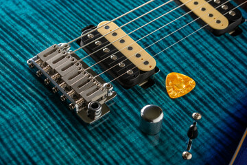 Detail of the neck, the pickup and the strings of a blue electric guitar