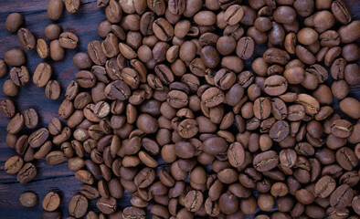 Background of roasted coffee beans scattered on a wooden surface.