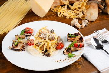 Homemade mushroom fettucini pasta. Delicious pasta served with tomatoes and peppers. Fresh Italian pasta.