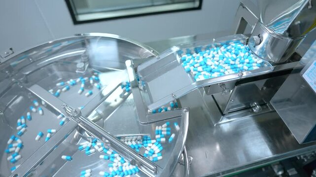 pills capsules manufacturing by a machine. automatic medicine tablet making machine. Production line at a pharmaceutical factory. close up machine medical tablets coming out.