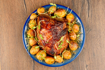 Freshly baked meat with baby potatoes and mini greens on a blue plate.