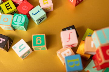Colorful alphabet blocks scattered on a golden surface Learning and fun