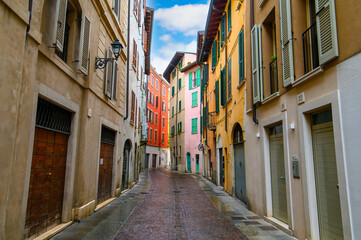 Brescia, Italy. Traditional colorful building with balconies, shutter windows and multicolored walls in typical italian street