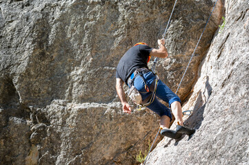 Climber with climbing harness equipment, climbing a rock wall. High quality photo