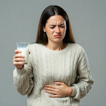 woman holding a glass of milk and suffering from stomack pain, lactose intolerance