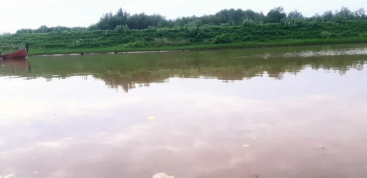 a fisherman is sailing on a river in a simple engine boat