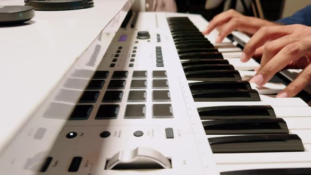 Fingers strike keys of white electronic keyboard