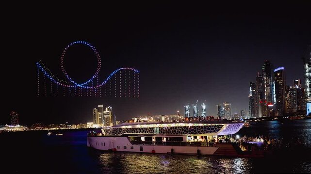 Drone show in night sky over Bluewaters and JBR Beach promoting Dubai Shopping Festival. People from pleasure yachts watch show. Taken from hands. High quality 4k footage