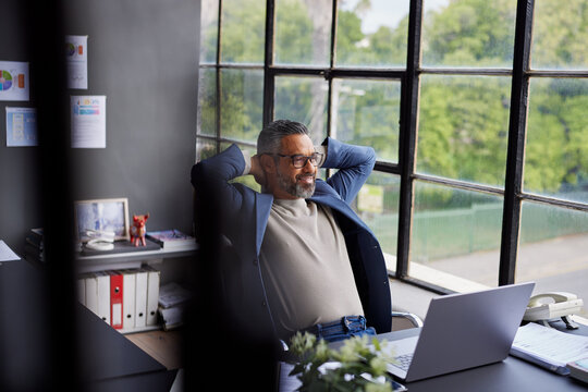 Mid adult businessman taking a break in his modern office - Powered by Adobe