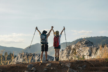 Young traveler couple standing on the edge of a mountain happily on vacation and enjoying the view