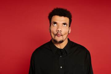 Obraz premium A young handsome man humorously contorts his face while looking upward, creating a fun atmosphere.
