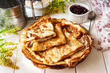 Delicious breakfast: Thin pancakes on a plate on a white table. Close-up.