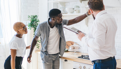Confident estate agent showing kitchen to African American attentive couple