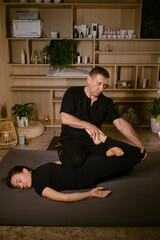 Male massage therapist performs back massage for pain treatment in spa. Thai massage with masseur in spa