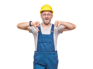 Smiling middle-aged construction worker showing thumbs down, dislike concept, isolated on white background. Craftsman against white wall