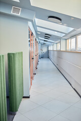 Vertical background shot of corridor with skylight windows and glass doors leading to individual...