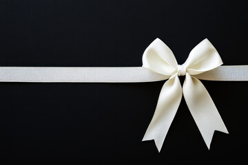 Elegant white bow tied on textured ribbon against a dark background highlights craftsmanship and decoration for various occasions