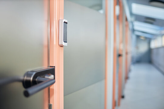 Background shot of NFC reader as part of security system installed on glass door leading to office room in contemporary business building, copy space