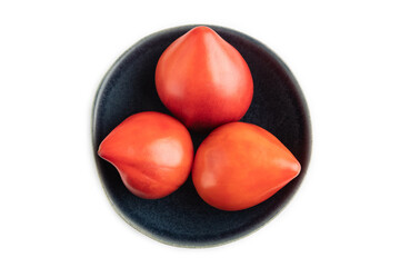 Red Heart shape tomatoes in blue bowl isolated on white. Top view, copy space