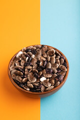wooden bowl with Kidney beans on blue and orange pastel paper, side view, copy space
