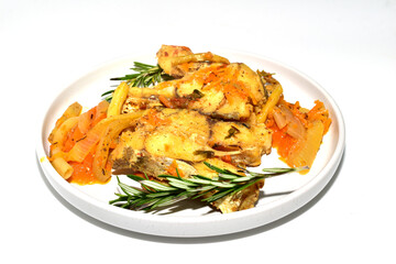 Cod fish with vegetables, ready to eat, lying on a plate, side view.